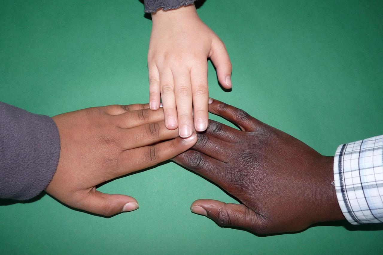 Bild mit drei Händen unterschiedlicher Hautfarbe zum Thema Integration