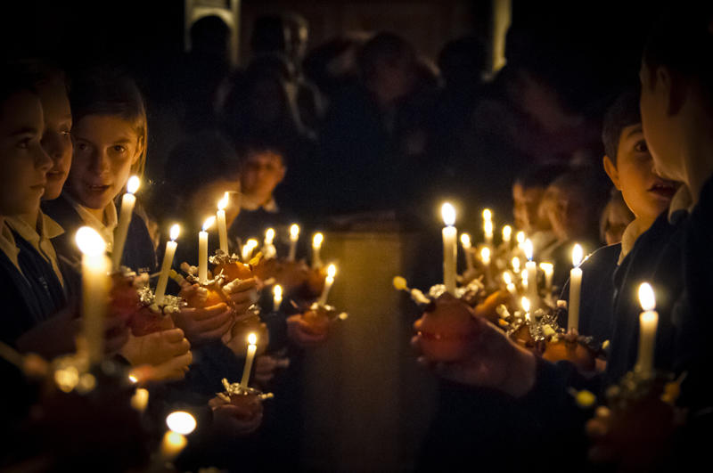 Jungen in Anzügen aus einem Chor halten Kerzen in der Hand.