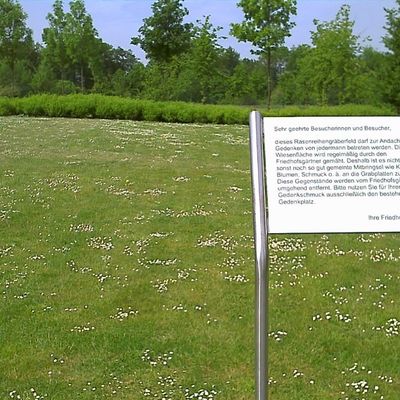 Bild von einem Rasenreihenfeld für Urnen und Särge mit dem Hinweisschild, dass nichts auf der Wiese abgelegt werden darf.