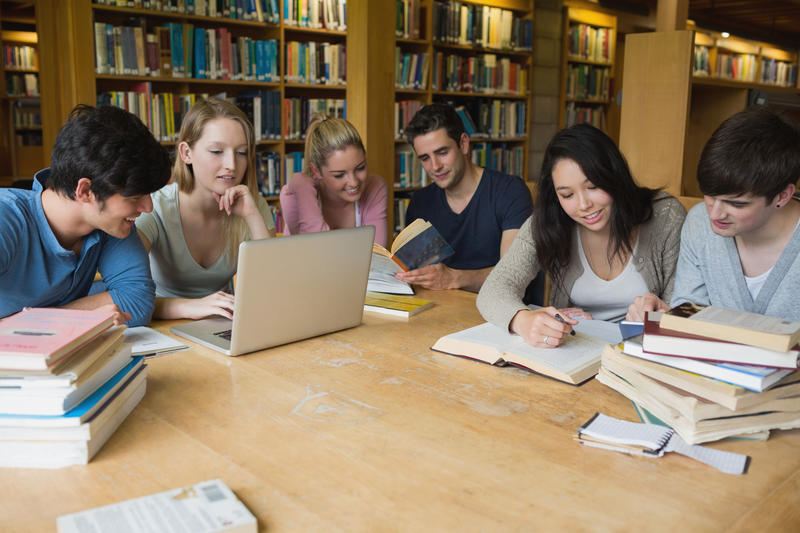 Eine Gruppe Studenten, die gemeinsam in der Bibliothek lernen.
