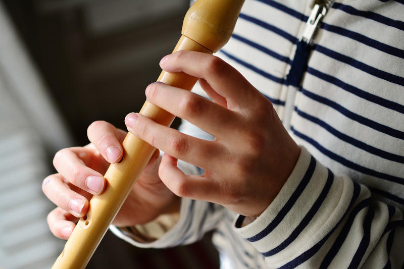 Das Bild zeigt ein Kind beim Flöte spielen.
