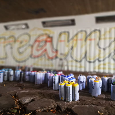Spraydosen vor einem Graffiti-Entwurf an der Wand.