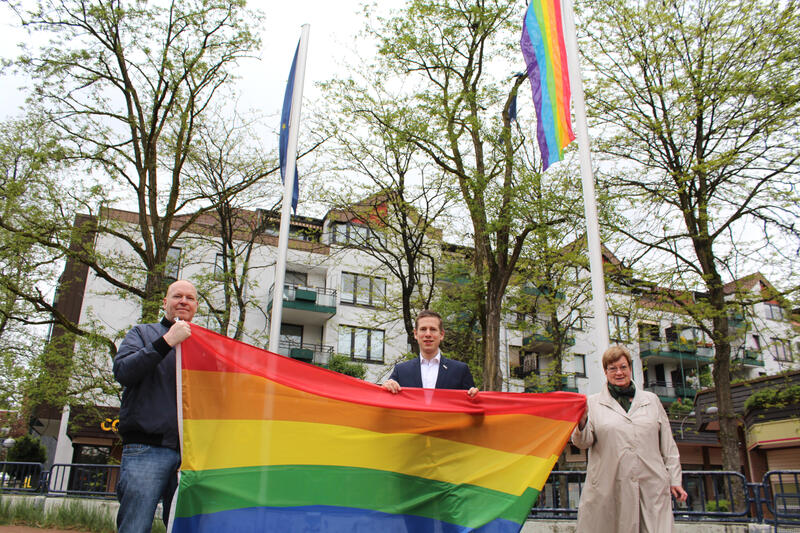 Bürgermeister Christoph Schultz (m.) und seine Stellvertretung Regina Wedding (r.) sowie Marc Göckeritz (l.) setzen gemeinsam ein Zeichen gegen Homophobie und Transphobie und hissen am Europaplatz in Hochdahl eine Regenbogenfahne.