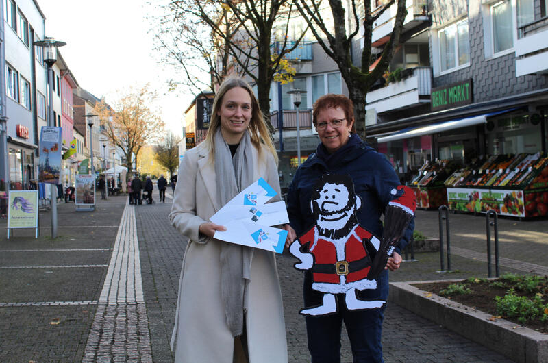 Citymanagerin Katharina Salzburg (l.) und Dorothea Mittemeyer (r.) von der städtischen Wirtschaftsförderung präsentieren den Neandertaler »Keulchen«, der im Zentrum des weihnachtlichen Gewinnspiels steht.