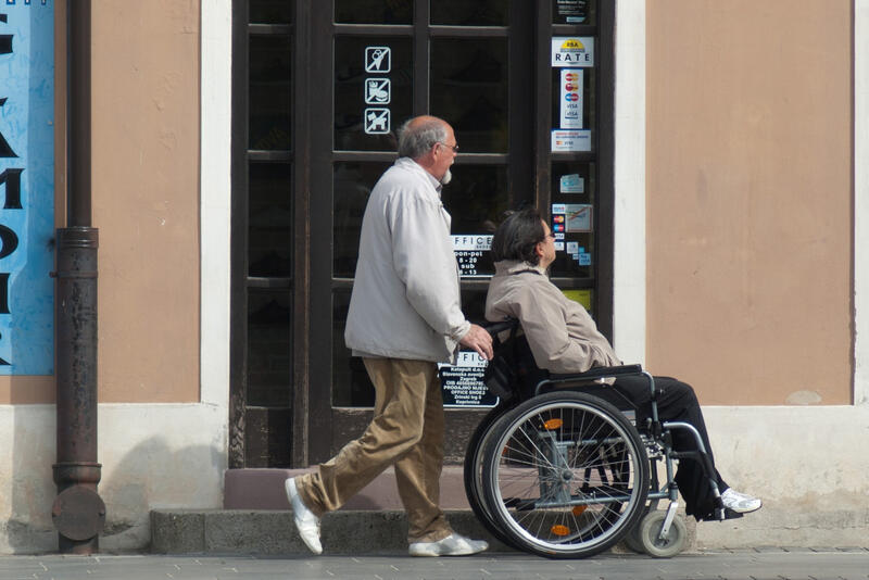 Das Bild zeigt einen Rollstuhlfahrer vor einem nicht barrierefreien Geschäftseingang.