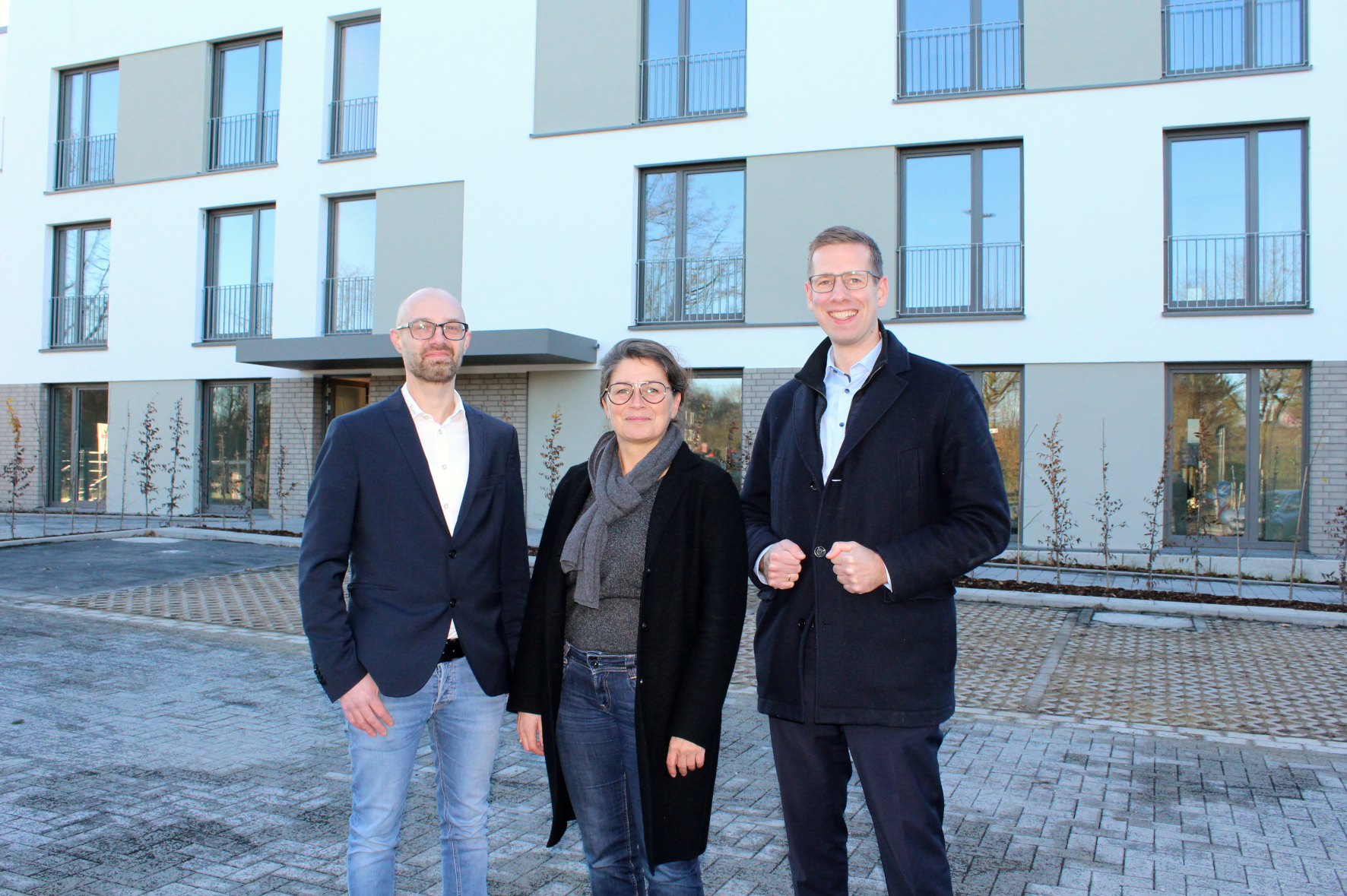 Bürgermeister Schultz, Beigeordnete Beck und Barthel freuen sich vor den neuen Wohneinheiten am Maiblümchen in Unterfeldhaus