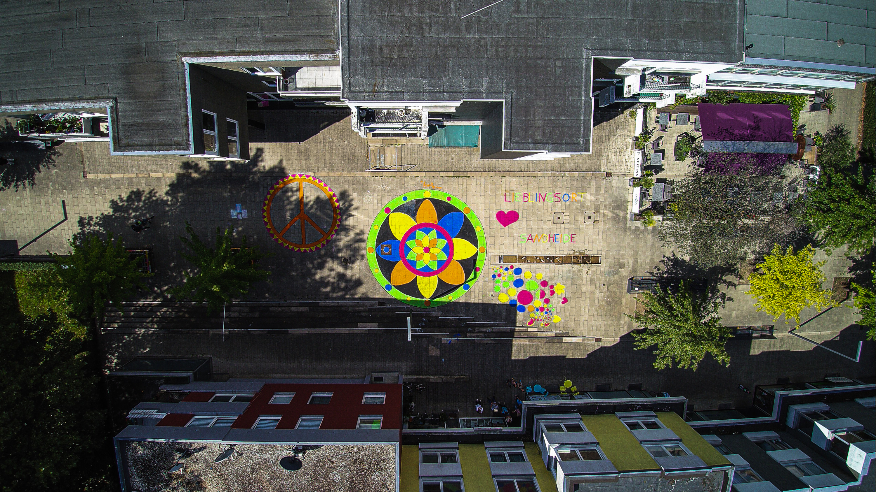 Eine Luftaufnahme von bunten Mandalas auf dem Sandheider Markt. Foto: Robin Schäfer