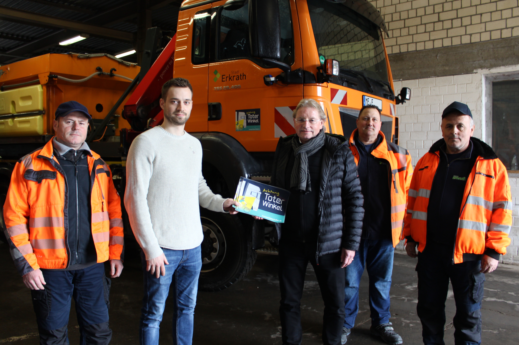 Der städtische Mobilitätsmanager Torben Priggert (2.v.l.) nimmt gemeinsam mit einigen Bauhof-Mitarbeitern die Aktionsaufkleber »Achtung: Toter Winkel« von Transportbotschafter und TIMOCOM-Gründer Jens Thiermann (3.v.l.) entgegen.