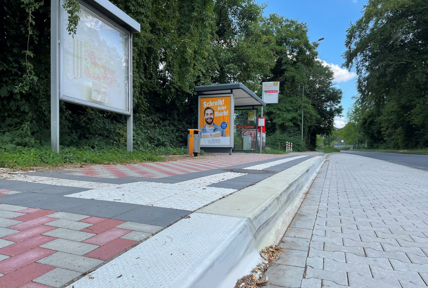 Das Foto zeigt eine barrierefreie Bushaltestelle mit mobilitätsgerecht angepasster Bordsteinkante sowie Blindenleitsystem.