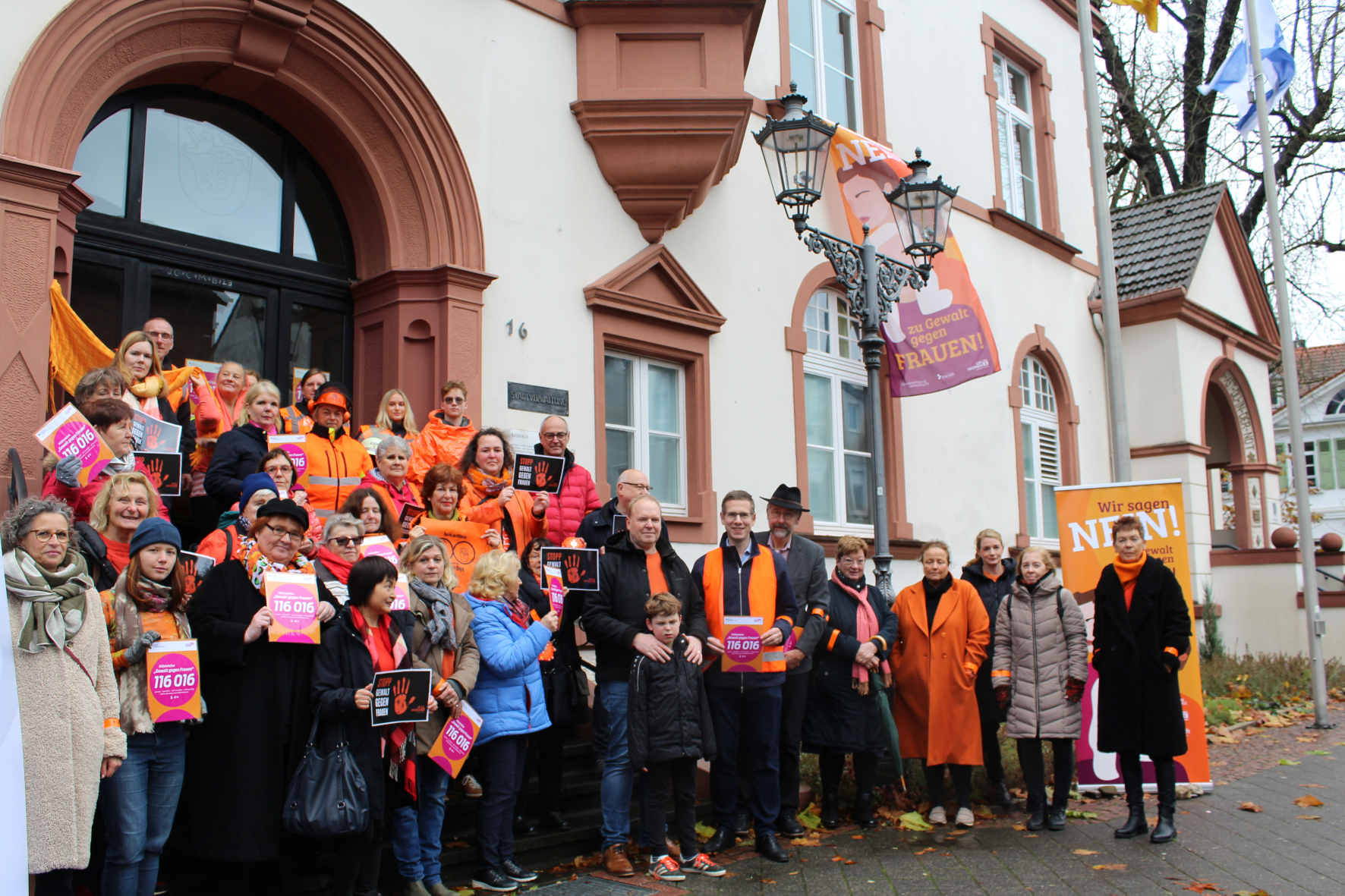 Gruppe an Menschen, die in orange gekleidet sind und Zettel in der Hand haben, um auf die "Orange Days" aufmerksam zu machen.
