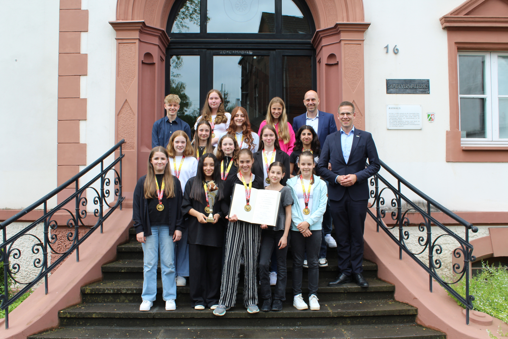 Floorballerinnen mit Medaille, dem Pokal und dem Goldenen Buch zusammen mit Bürgermeister Christoph Schultz vor dem Rathaus.