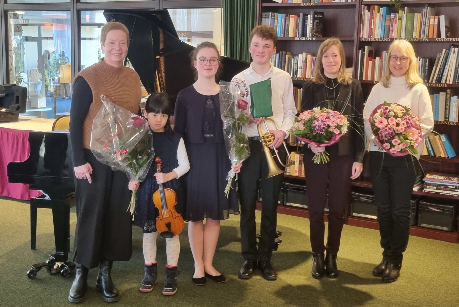 Christine Teinze (2.v.l.) und Sophia Amelingmeyer (3.v.l.) stehen mit weiteren Musikerinnen vor einem Flügel. Sie halten Blumen in den Händen.