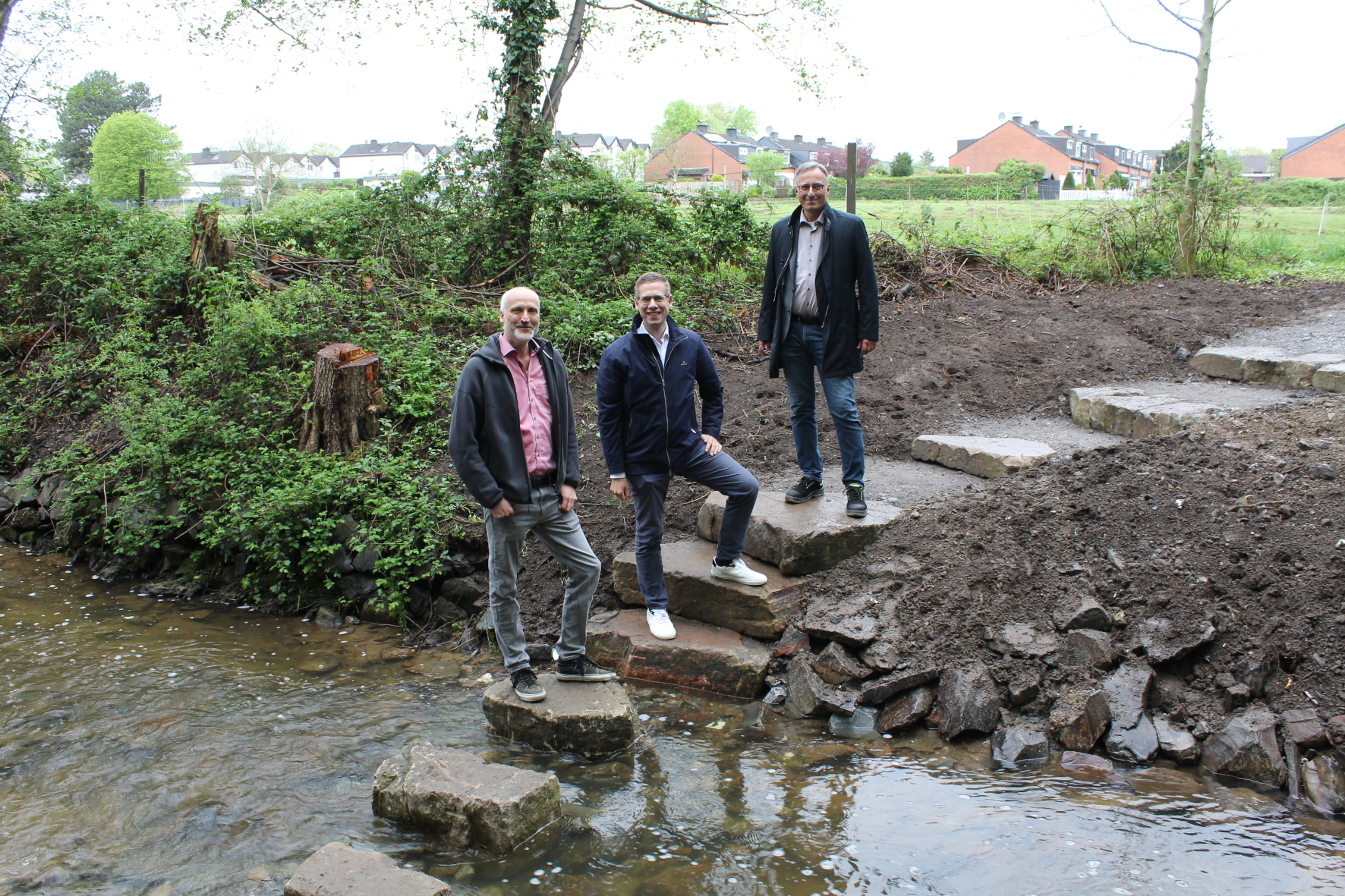 In Unterfeldhaus ermöglichen mehrere große Trittsteine eine Querung des Eselsbachs. Bürgermeister Christoph Schultz (M.) und Sven Wernke, Abteilungsleiter Straßen (l.), bedankten sich bei Engin Alparslan (r.) vom BRW für die gelungene Umsetzung.