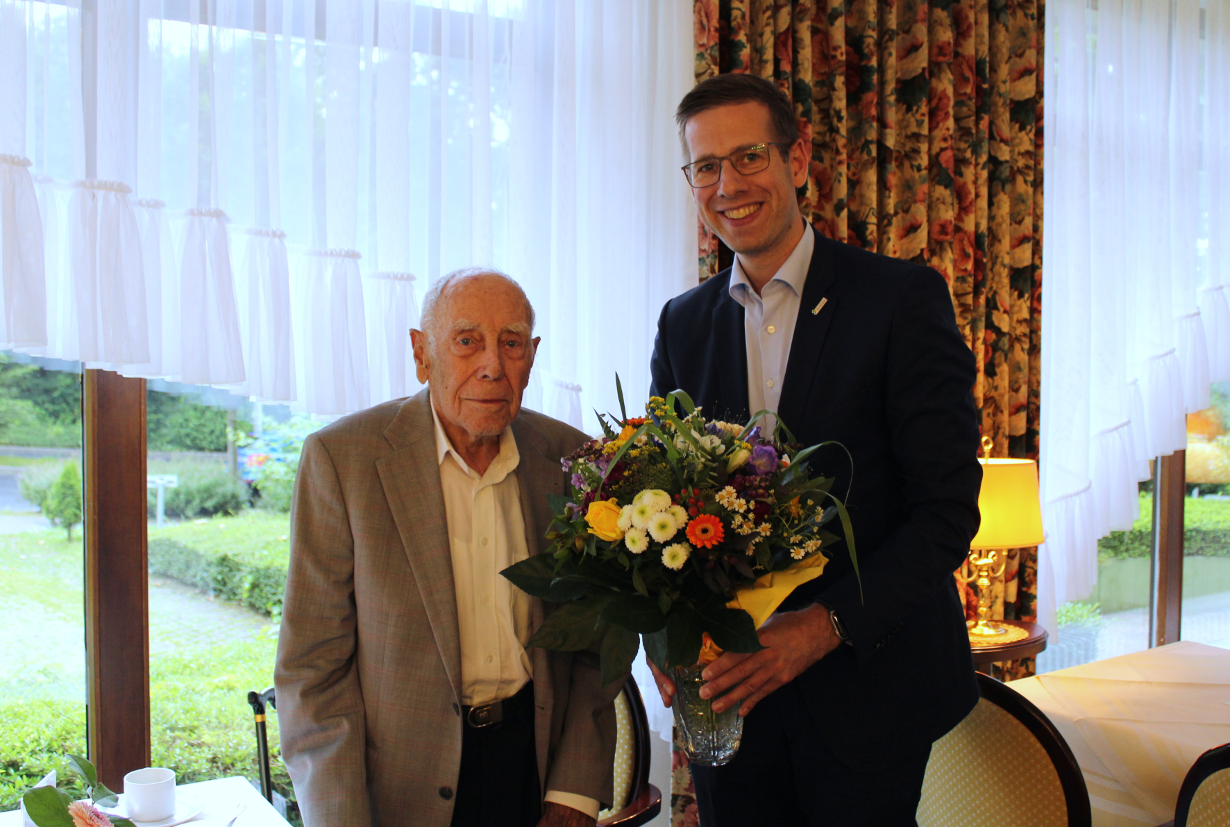 Bürgermeister Christoph Schultz übergibt Blumenstrauß an Paul Neumann zum 101. Geburtstag.