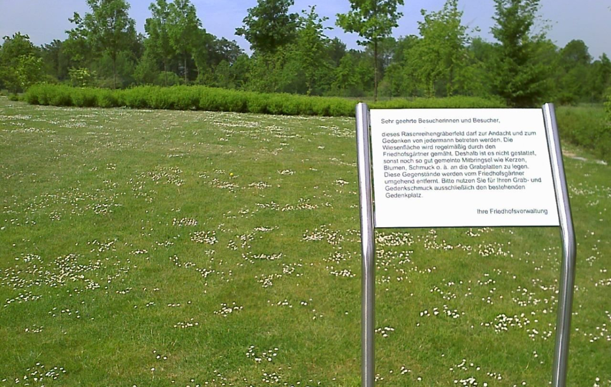 Bild von einem Rasenreihenfeld für Urnen und Särge mit dem Hinweisschild, dass nichts auf der Wiese abgelegt werden darf.