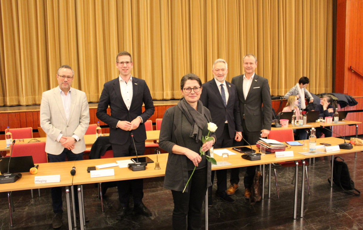 Carola Beck mit einer weißen Rose vor Tischen
