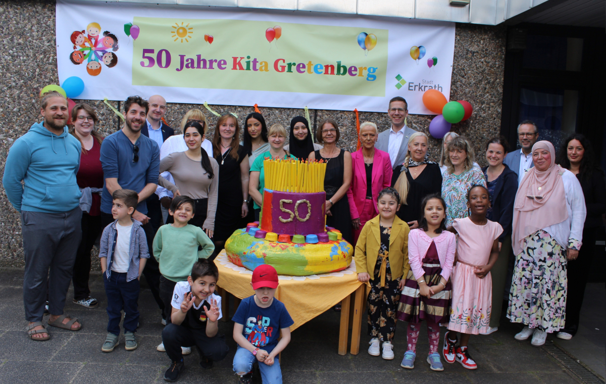 Kinder und Erwachsene feiern mit einer großen bunten Tortenskulptur 50-jähriges Bestehen der Kita Gretenberg