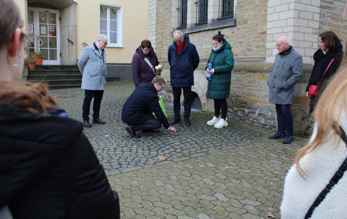 Bürgermeister Christoph Schultz und Mitglieder der Ratsparteien reinigen einen Stolperstein in Erkrath.