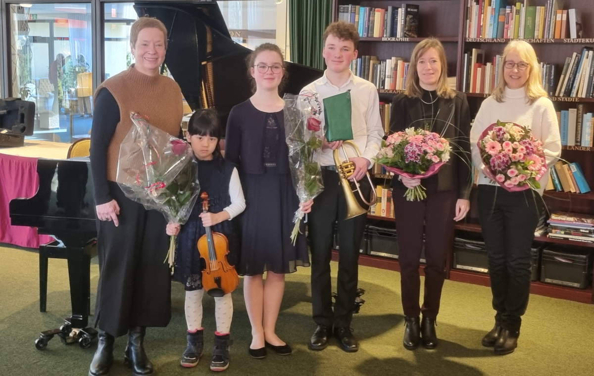 Christine Teinze (2.v.l.) und Sophia Amelingmeyer (3.v.l.) stehen mit weiteren Musikerinnen vor einem Flügel. Sie halten Blumen in den Händen.