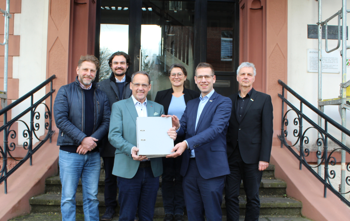 Bürgermeister Christoph Schultz (vorne rechts) überreicht an Catella-Geschäftsführer Klaus Franken (vorne links) die Baugenehmigung zur Realisierung der »Düssel-Terassen« am Wimmersberg in Alt-Erkrath.