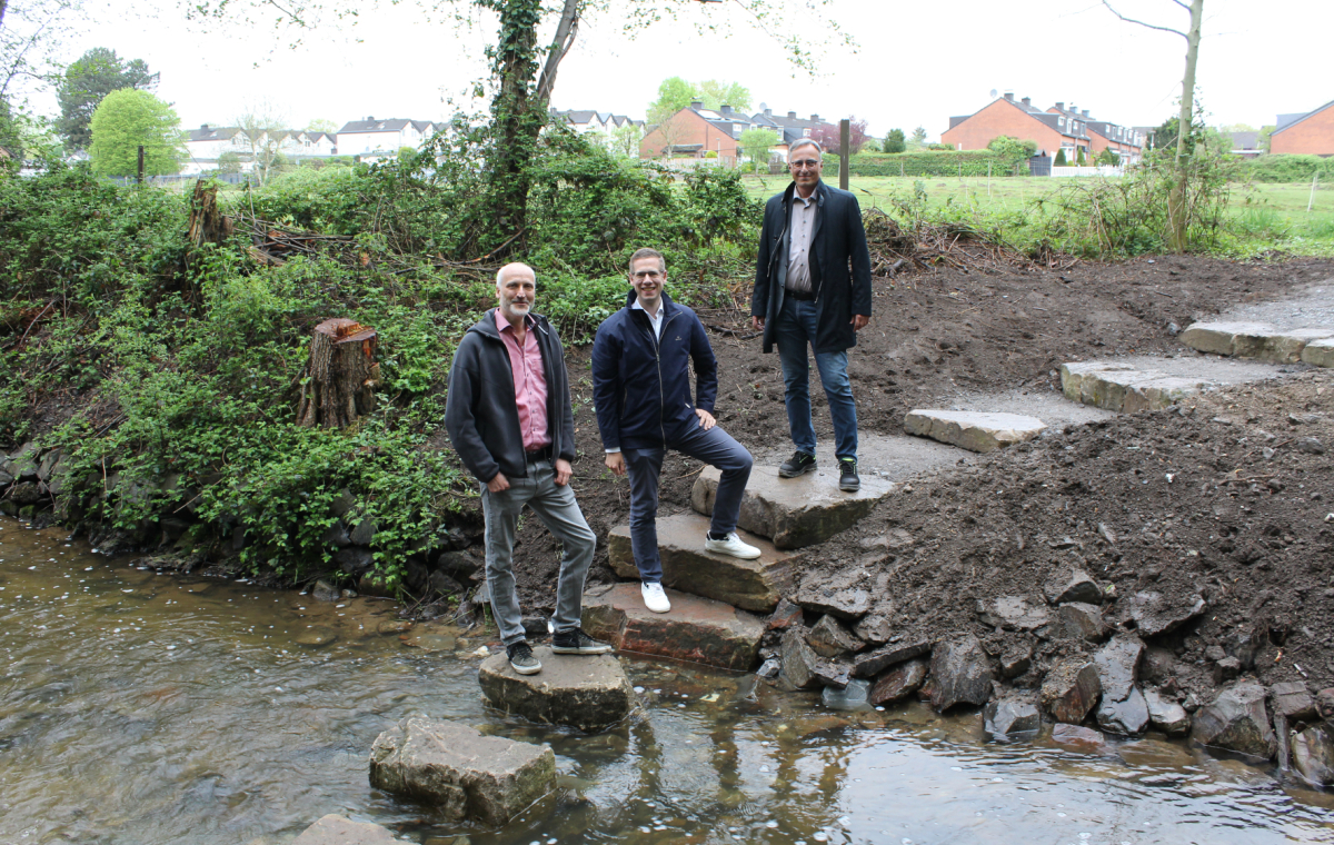 In Unterfeldhaus ermöglichen mehrere große Trittsteine eine Querung des Eselsbachs. Bürgermeister Christoph Schultz (M.) und Sven Wernke, Abteilungsleiter Straßen (l.), bedankten sich bei Engin Alparslan (r.) vom BRW für die gelungene Umsetzung.