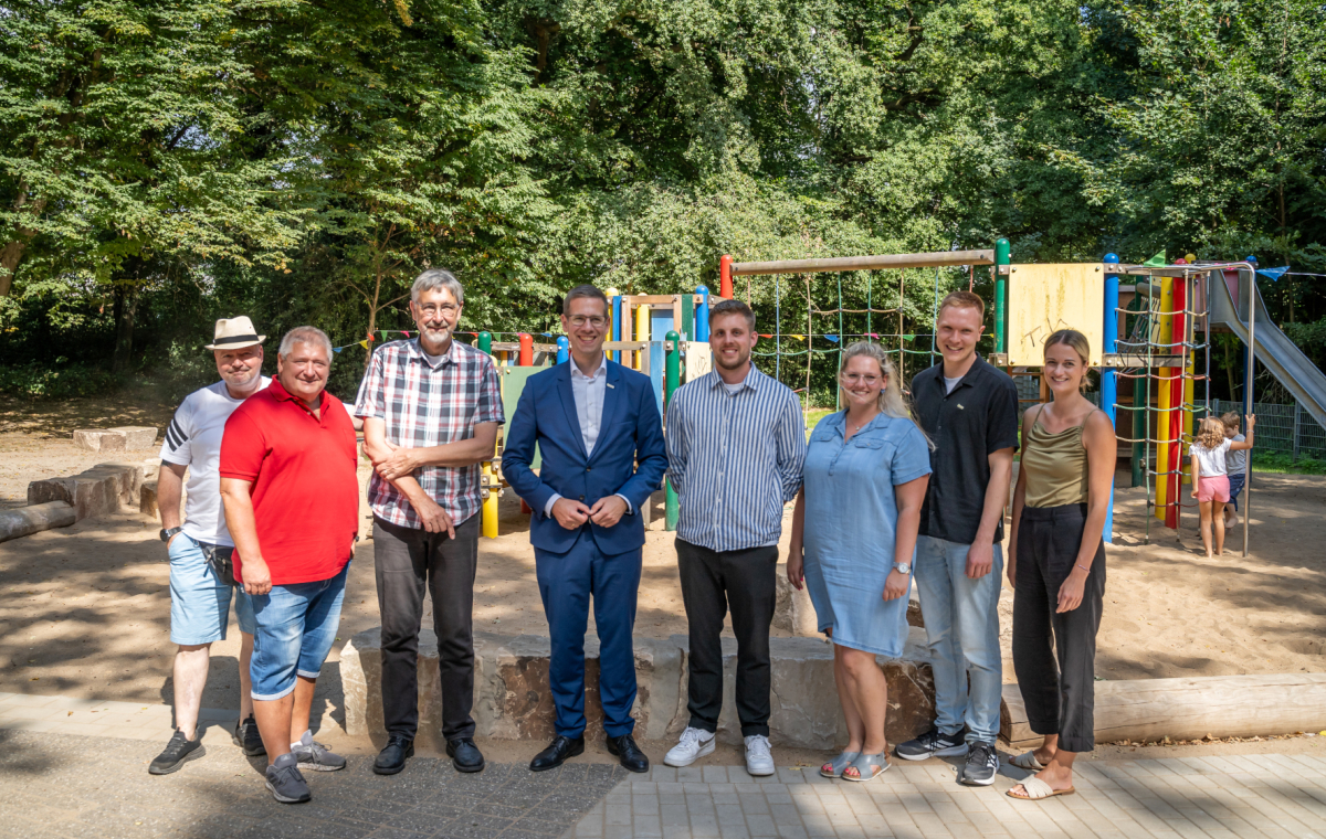 Bürgermeister Christoph Schultz (4.v.l.) eröffnete gemeinsam mit den am Projekt beteiligten Personen und mehreren neugierigen Kindern den neugestalteten Spielplatz Gretenberg in Hochdahl.